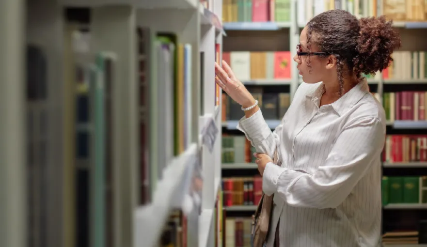 Imagem de Jovem pesquisando livros na biblioteca 