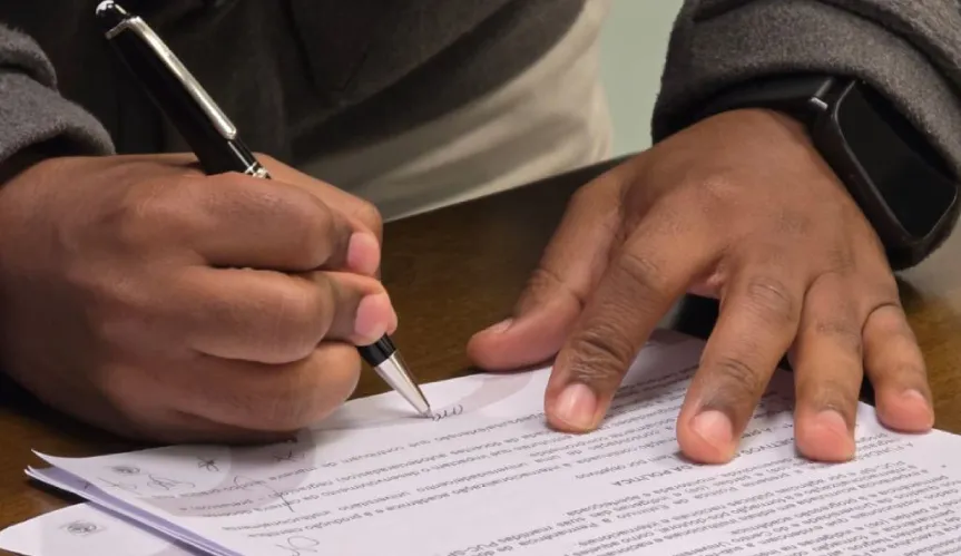 imagem de mãos de uma pessoa negra assinando um contrato 